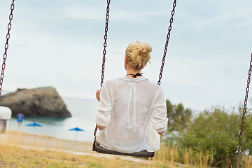 Image showing Young blonde woman sitting on the swing