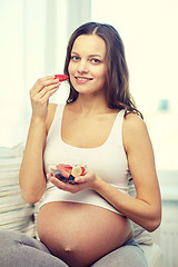 Image showing happy pregnant woman eating fruits at home