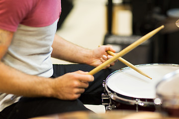 Image showing close up of musician with drumsticks playing drums