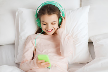 Image showing happy girl lying in bed with smartphone at home