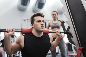 Image showing man and woman with barbell flexing muscles in gym