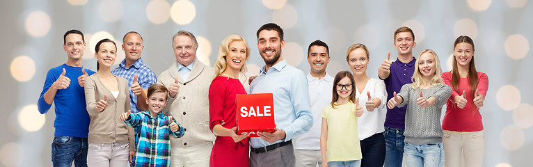 Image showing happy people with red sale sign showing thumbs up