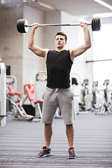 Image showing young man flexing muscles with barbell in gym