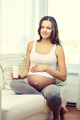 Image showing happy pregnant woman drinking milk at home