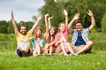 Image showing group of smiling friends waving hands outdoors