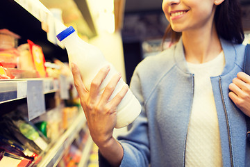 Image showing happy woman holding milk bottle in market