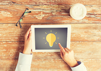 Image showing close up of hands with lighting bulb on tablet pc