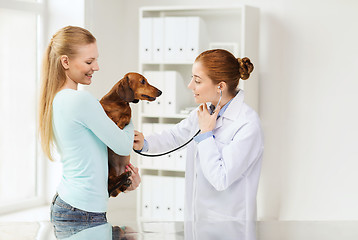 Image showing happy woman with dog and doctor at vet clinic