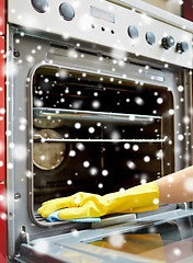 Image showing close up of woman cleaning oven at home kitchen