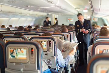 Image showing Steward and passengers on commercial airplane.