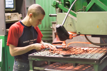 Image showing Worker operates computerized metalworking machine