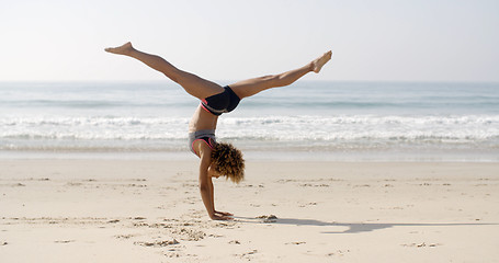 Image showing Young Woman Doing Cartwheel On The Beach