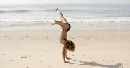 Image showing Young Woman Doing Cartwheel On Beach