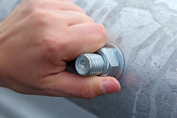 Image showing metal nut to the bolt by hand wound in the pipe.