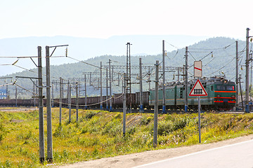 Image showing Big green electric locomotive with cars going by rail