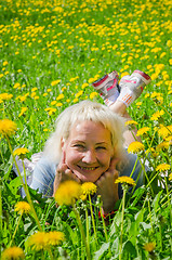 Image showing A woman lies in a clearing and sniffs a flower  