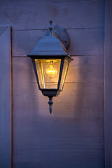 Image showing Old lantern burning on the wooden walls