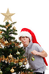 Image showing Boy with santa hat sticking out tongue at  the Christmas tree