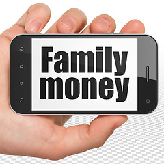 Image showing Currency concept: Hand Holding Smartphone with Family Money on display