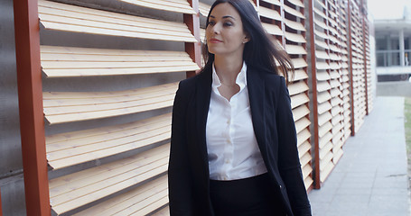 Image showing Attractive young woman striding through town