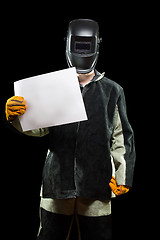 Image showing handsome welder holding a blank form. isolated on black background