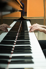 Image showing Women\'s hands on the keyboard of piano. girl plays music 