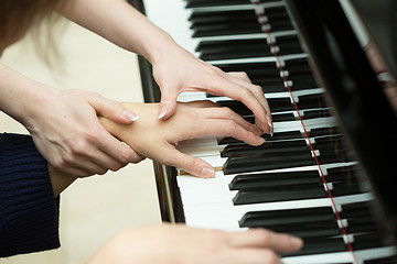 Image showing Women\'s hands on the keyboard of piano. girl plays. music teacher