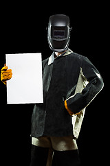 Image showing handsome welder holding a blank form. isolated on black background