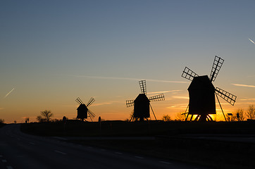 Image showing Windmills silhouettes by roadside at sunset