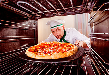 Image showing Chef cooking pizza in the oven.