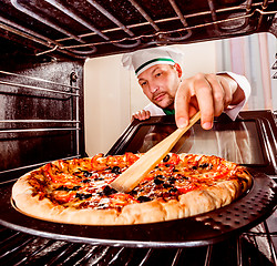 Image showing Chef cooking pizza in the oven.