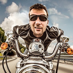 Image showing Funny Biker in sunglasses and leather jacket racing on mountain 