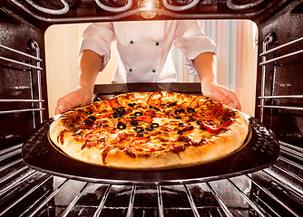 Image showing Chef cooking pizza in the oven.