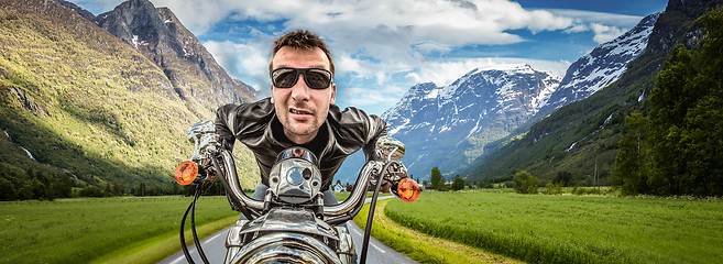 Image showing Funny Biker in sunglasses and leather jacket racing on mountain 