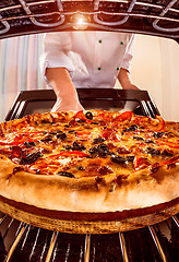 Image showing Chef cooking pizza in the oven.