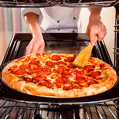 Image showing Chef cooking pizza in the oven.