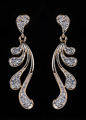 Image showing gold earrings with jewels on the black