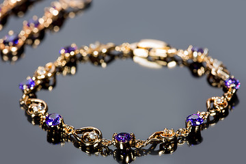 Image showing gold bracelet on gray background. 