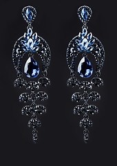 Image showing earring with colorful blue gems on black background