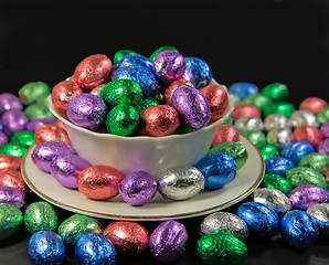 Image showing overflowing bowl and plate of easter eggs on black