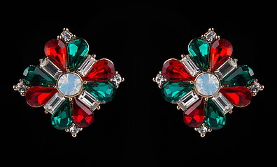 Image showing earring with colorful red and green gems on black background
