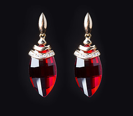 Image showing earring with colorful red gems on black background