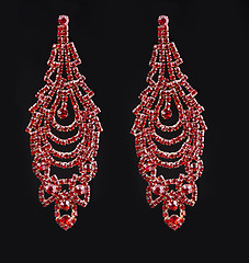 Image showing earring with colorful red gems on black background