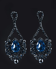 Image showing earring with colorful blue gems on black background