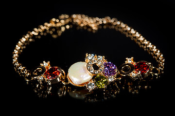 Image showing golden bracelet with precious stones on black background