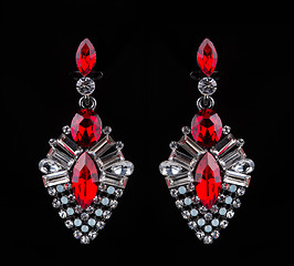 Image showing earring with colorful red gems on black background