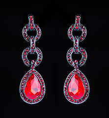 Image showing earring with colorful red gems on black background