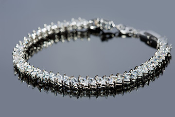 Image showing silver bracelet with diamonds on gray background. 