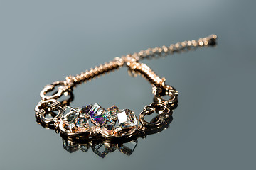 Image showing golden bracelet with precious stones on grey background