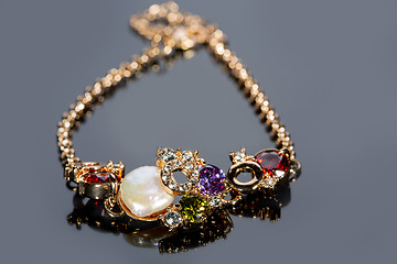 Image showing golden bracelet with precious stones on grey background